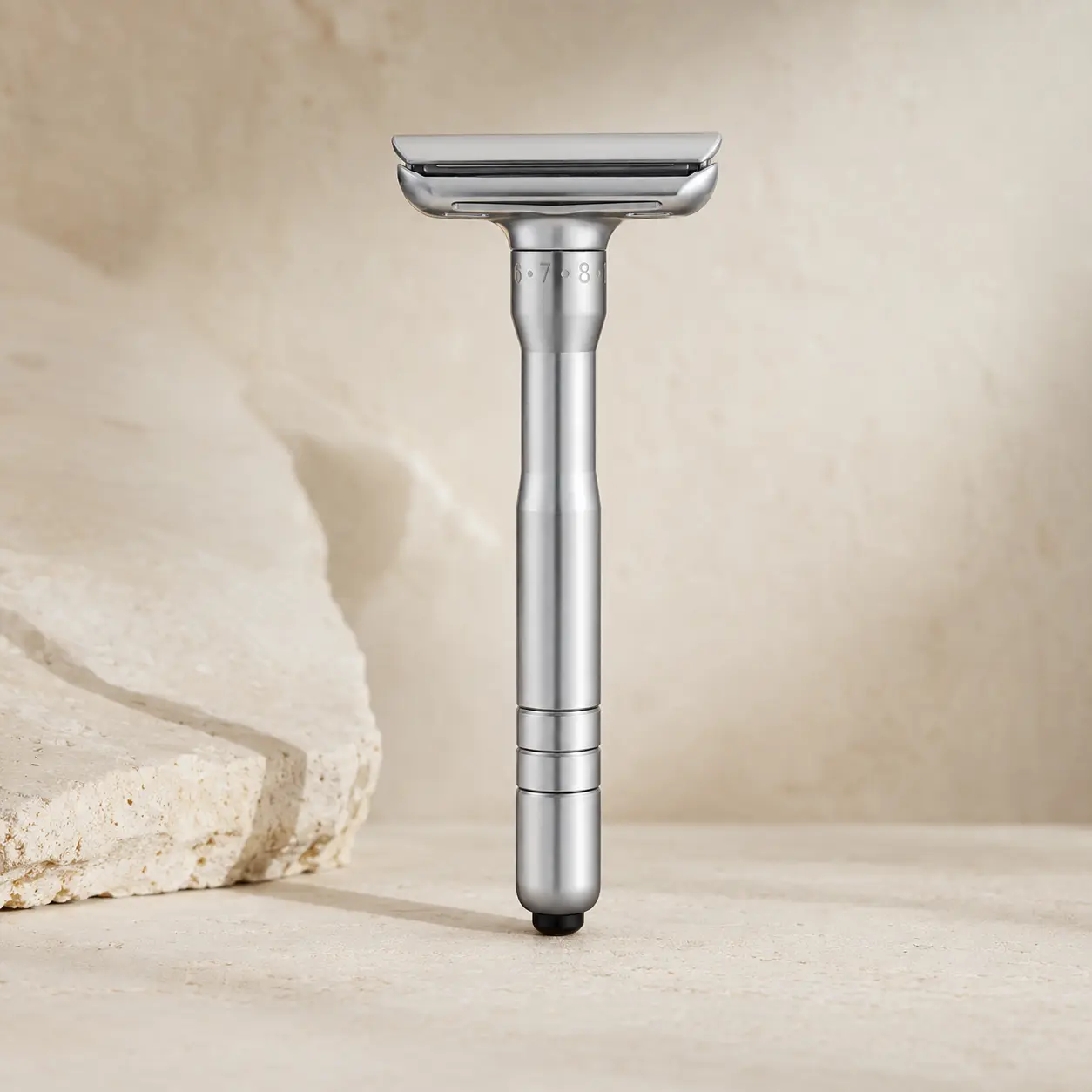 Ritual Eight adjustable safety razor standing upright on warm ivory limestone